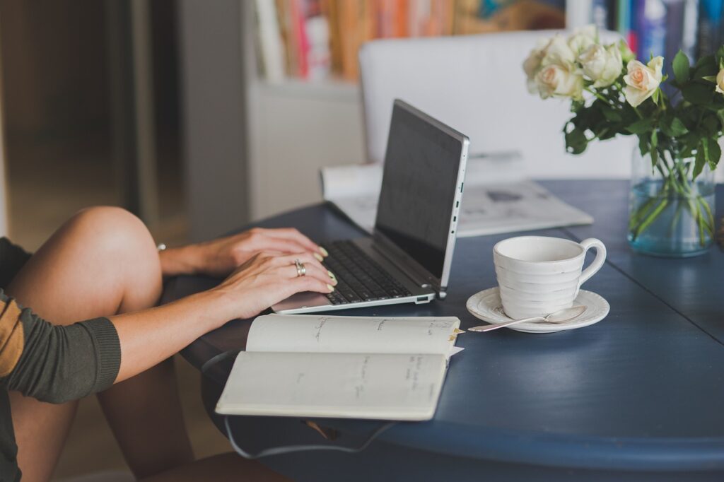 person writing a professional cover letter at a desk with a laptop and coffee