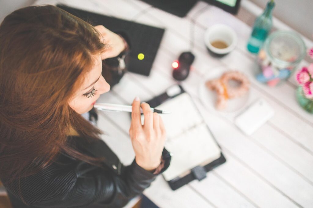 professional person writing cover letter at desk laptop notebook